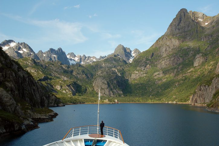 Person admiring fjord from ship deck
