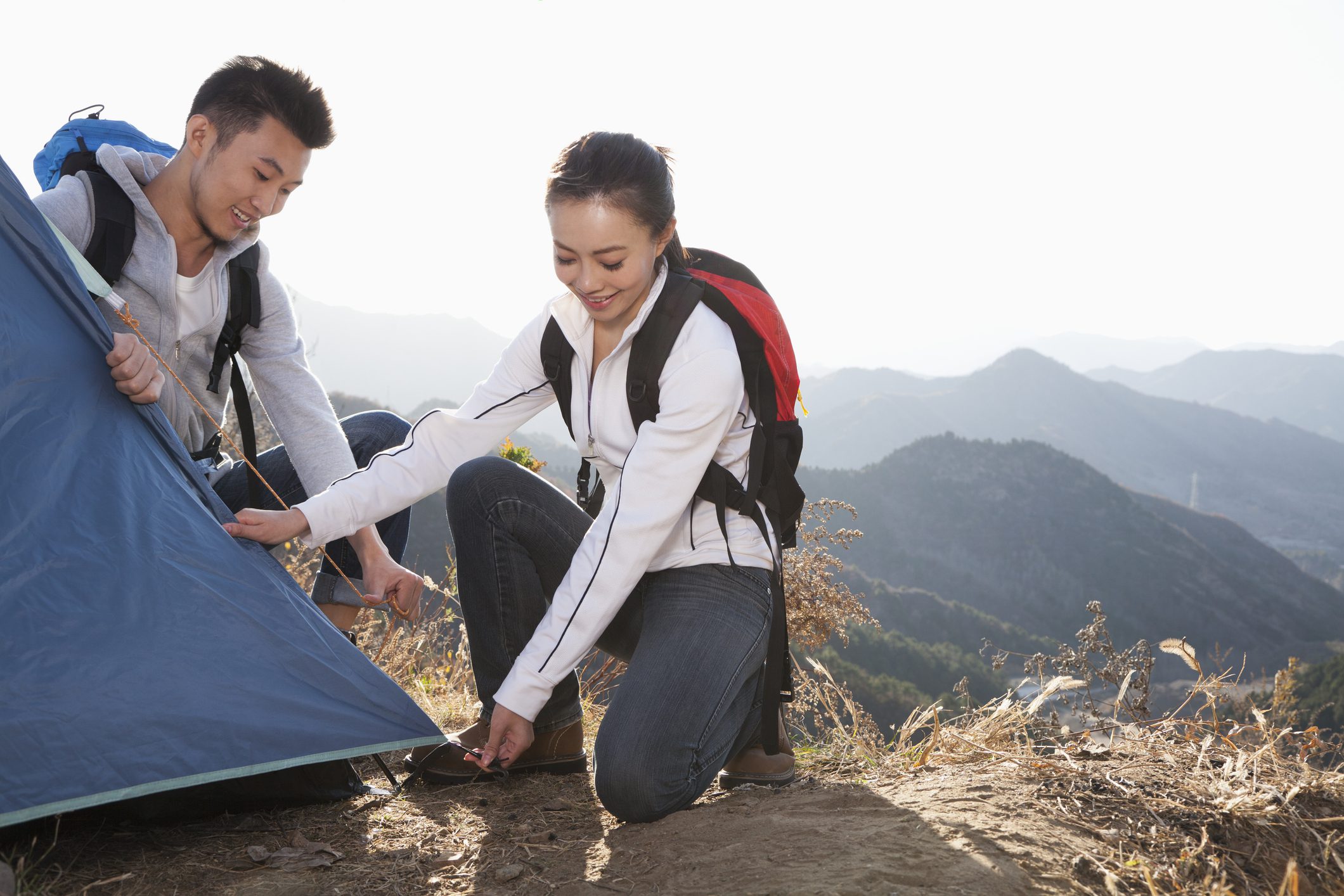 Couple setting up tent in mountains
